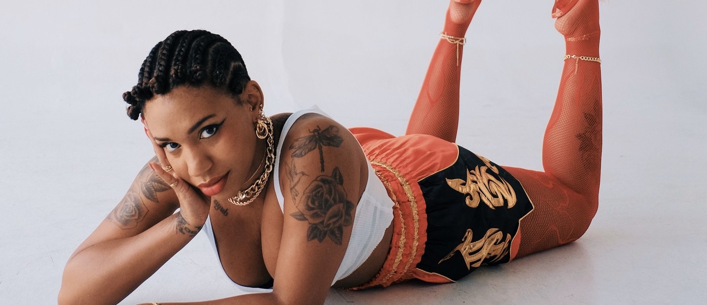 Studio portrait of Yaya Bey laying down on her stomach, gazing toward the camera.