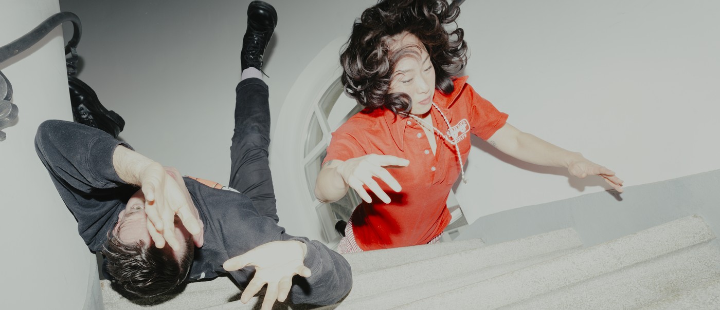 Experimental action shot of duo Xiu Xiu lying down on a set of stairs, with arms extended