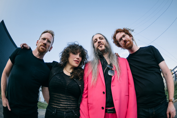 A colour fisheye photo taken from below shows four-piece band lushclot standing outside with a blue sky behind them.